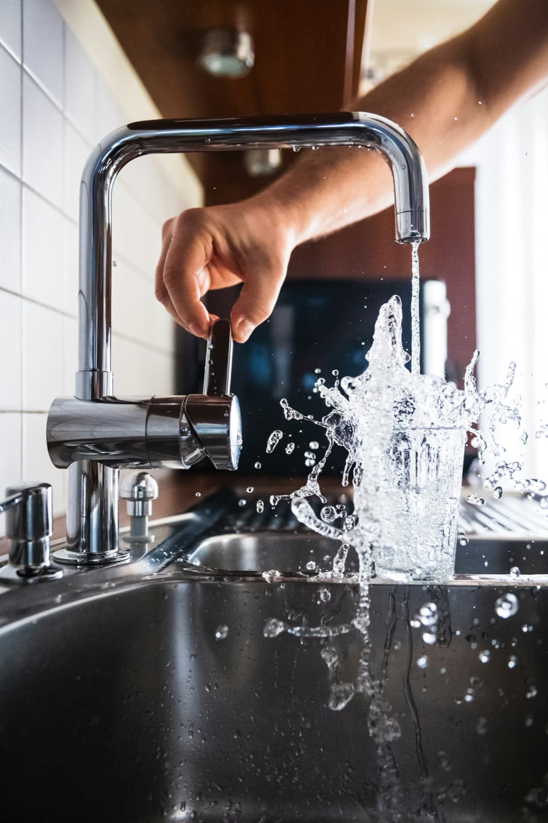 Plumber repairing pipes under a sink (illustrative photo)